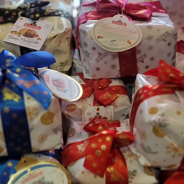Italian panettone and pandoro cakes from Albertengo, wrapped with festive bows, on display at Tino's Delicatessen.